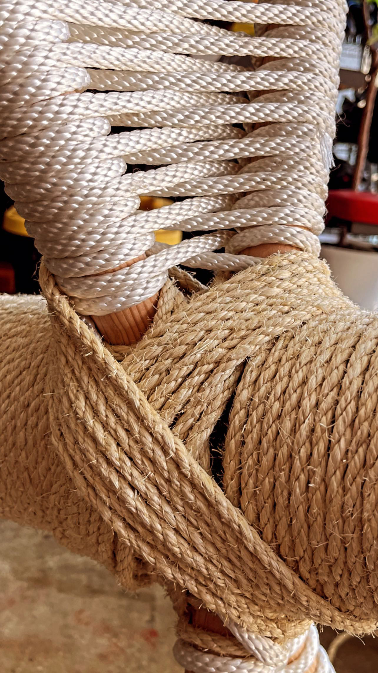 Close-up of white woven rope crossing over the natural jute wrap on the cat tree.