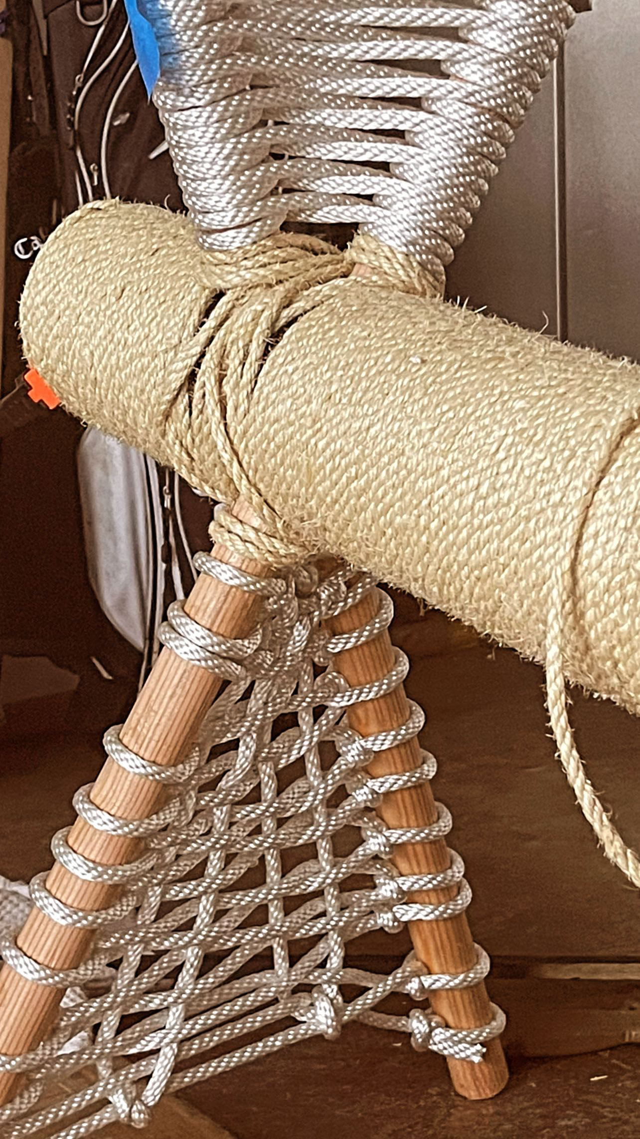 The woven rope hammock platform structure close up, with white rope strung between wooden dowels.