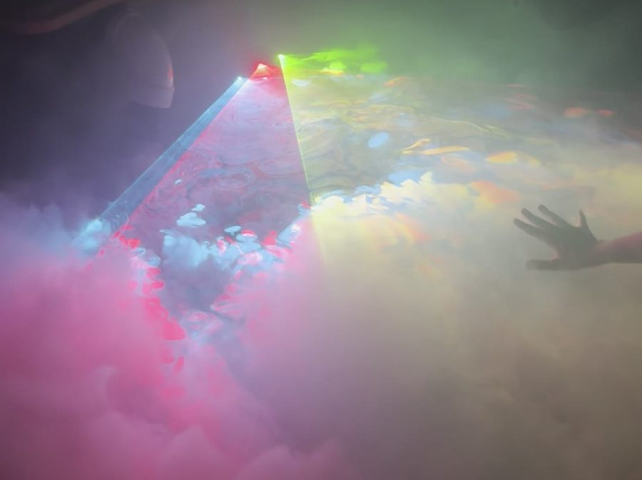 A hand reaching through low fog under laser light