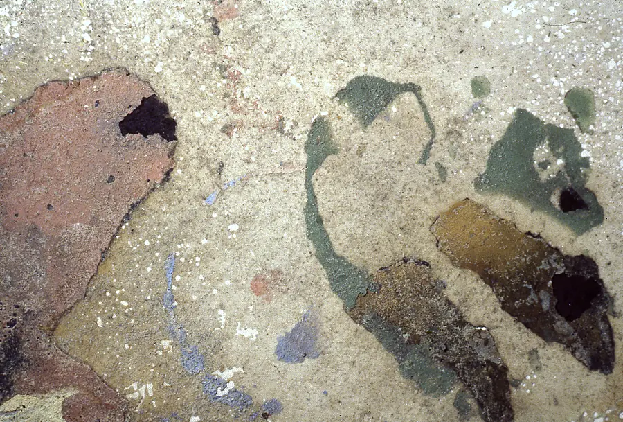 Detail of a peeled paint surface in terracotta, green, ochre and cream.