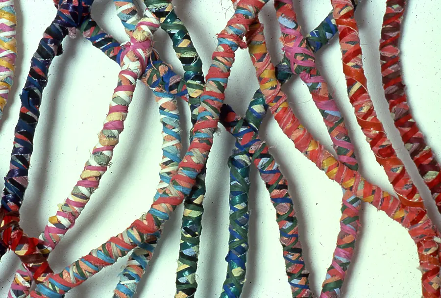 Close-up of curving ropes tightly wrapped in red, blue, green and pink cloth.