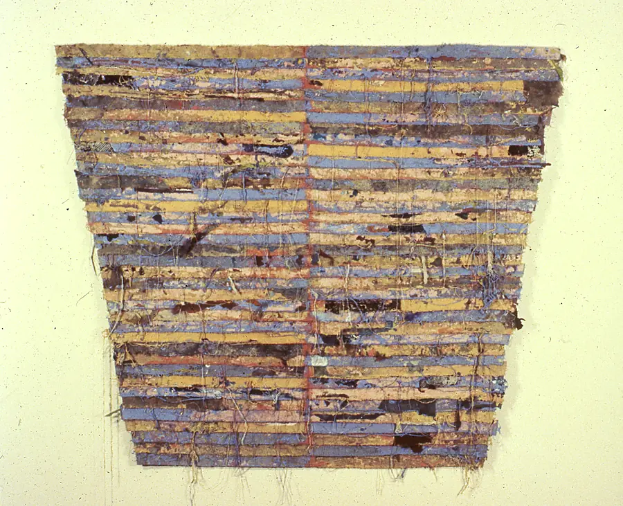 Trapezoid wall piece of stacked ochre, periwinkle, pink and brown canvas strips divided by a thin red seam, with threads hanging below.