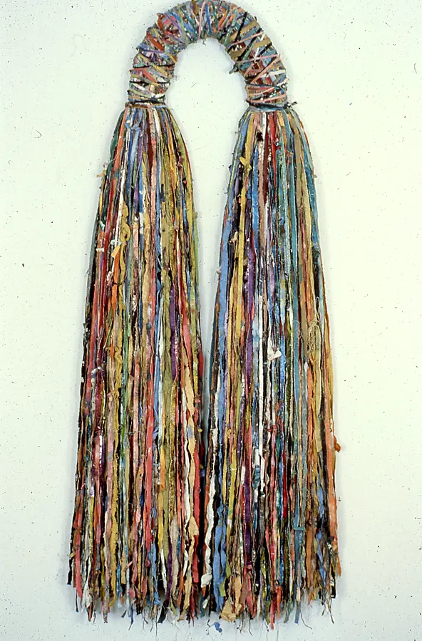 Small wrapped arch opening into two long curtains of red, orange, blue, yellow and green strips.