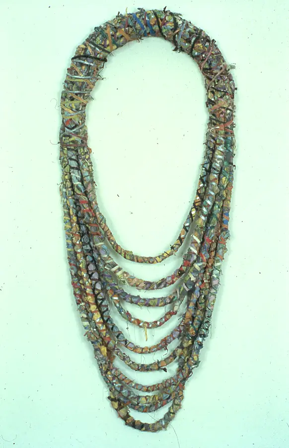 Wall piece of nested oval loops of wrapped strips, like a heavy necklace.