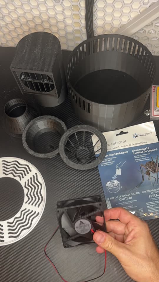 All the printed parts, the fan and the bait laid out on a desk